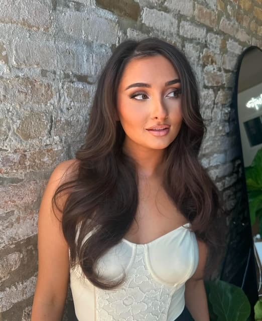 Stefania showing her Glowout spray tan beside the studio brick wall