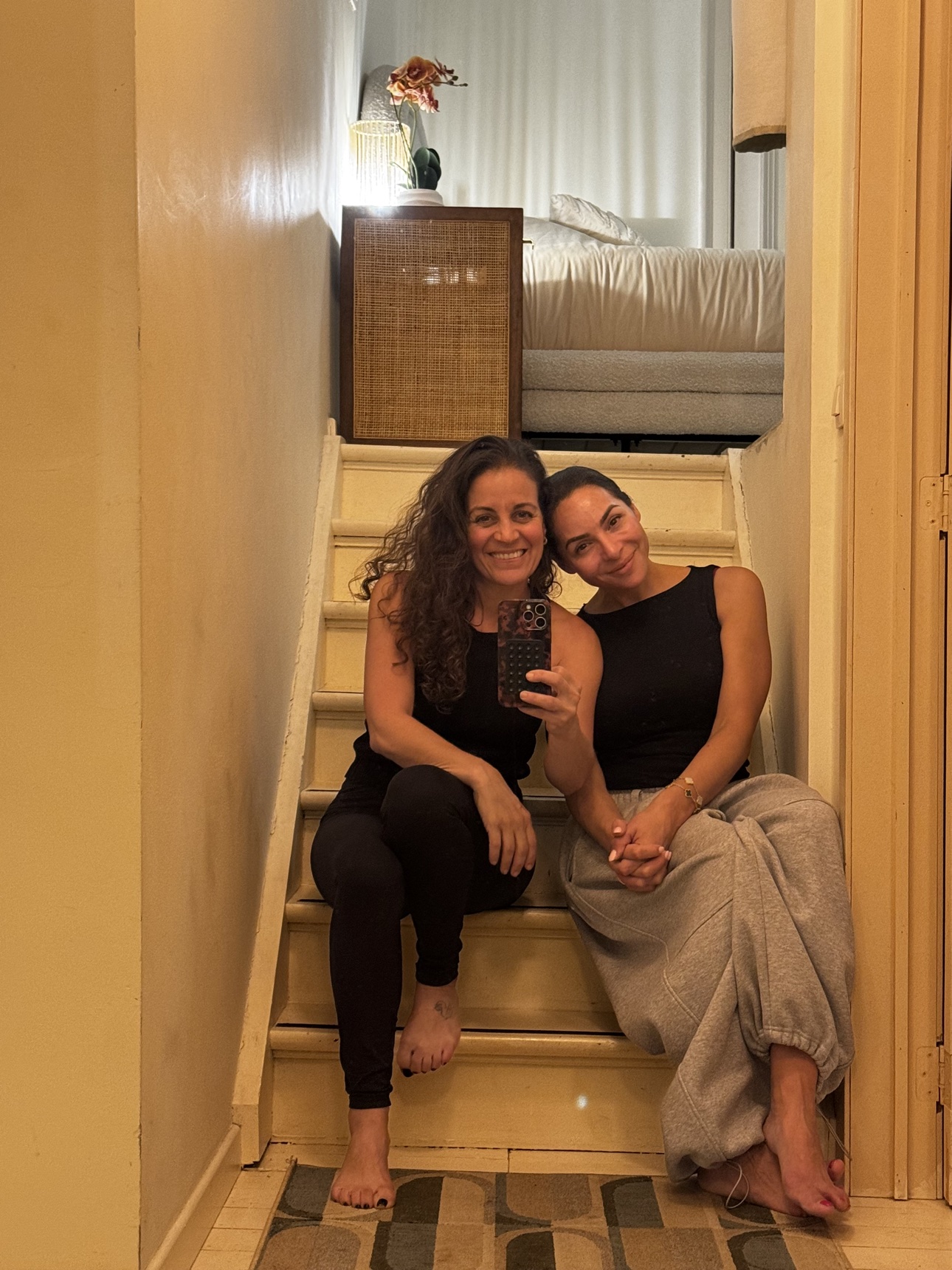 Two friends sitting together on a staircase for a mirror selfie
