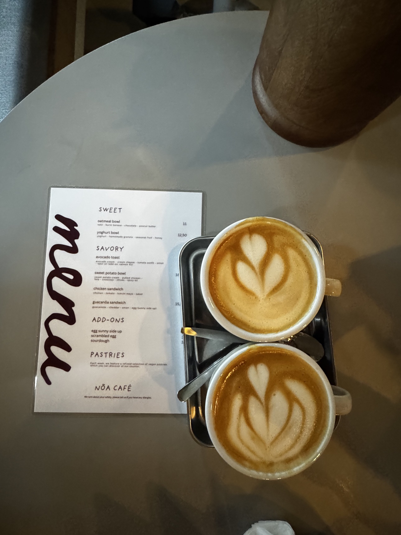Two cappuccinos beside a handwritten café menu