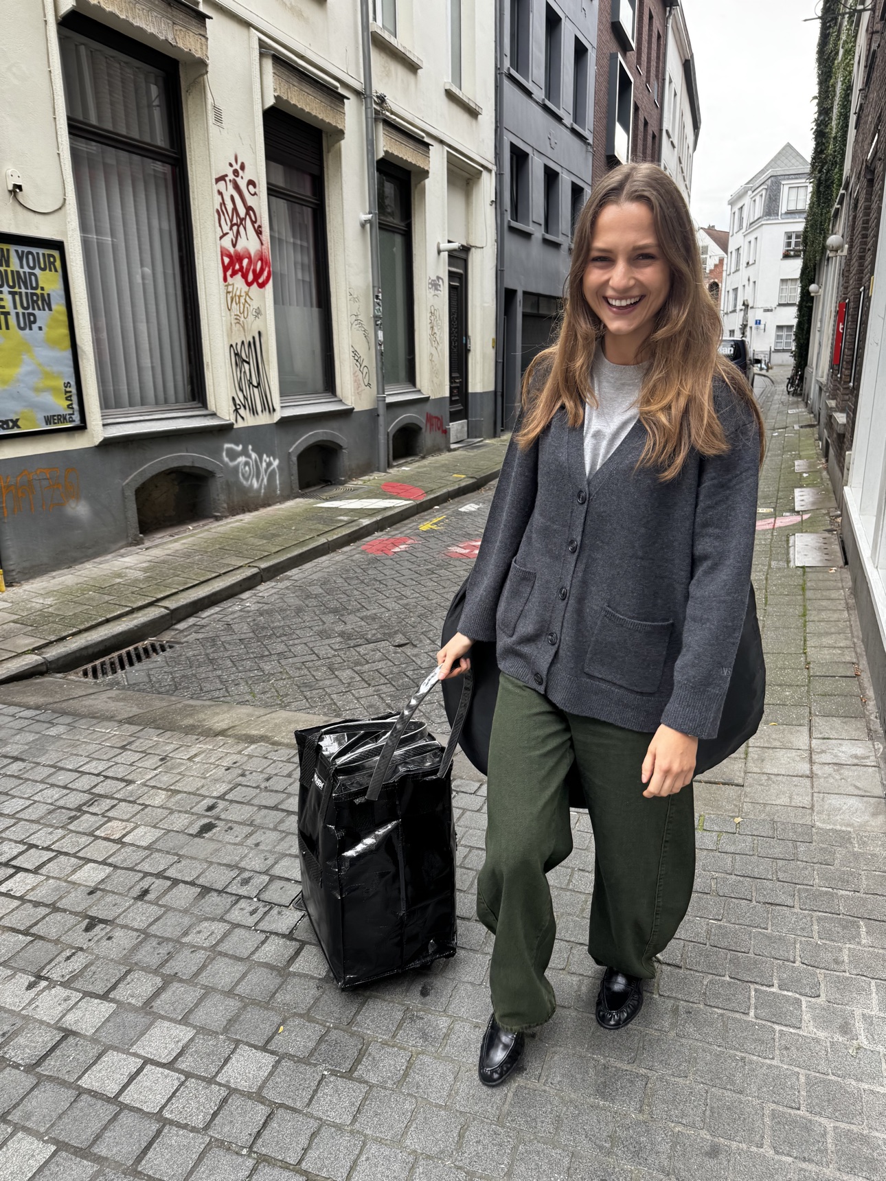 A smiling tour guest rolling her kit along an Antwerp street