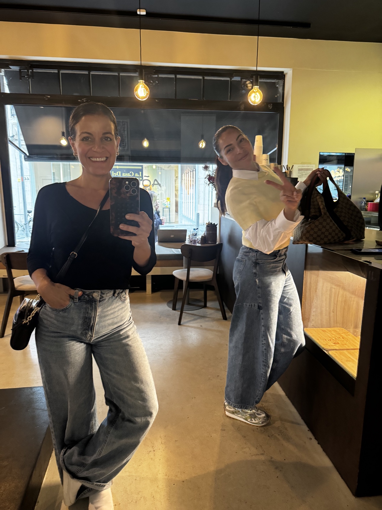 Two women smiling together inside a coffee shop