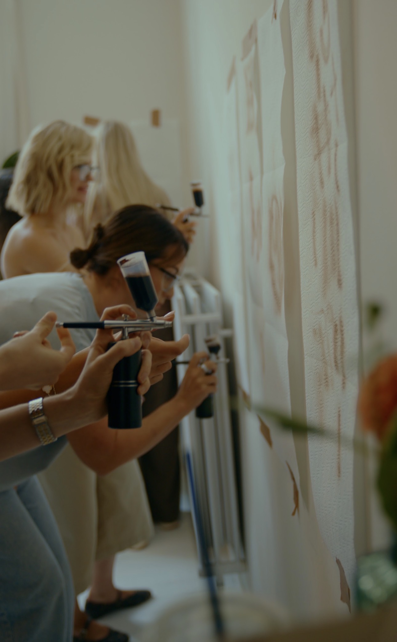 Artists practicing spray tan application together during hands-on training in Antwerp