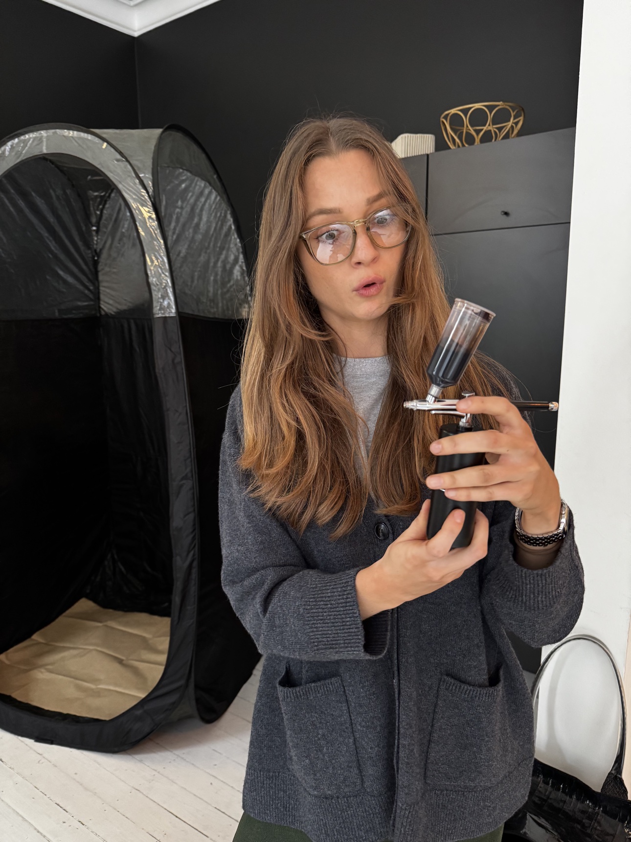 Spray tan artist examining the spray gun during training